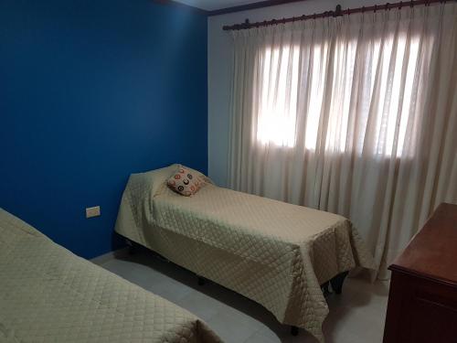 Habitación azul con 2 camas y ventana en Casa Cerro de la Luna en Salta