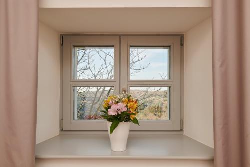 eine Vase voller Blumen vor einem Fenster in der Unterkunft B&B Artegnana 1798 in Grožnjan