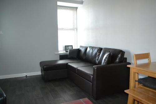 a black leather couch in a living room with a window at Harbour View Apartment Wick in Wick