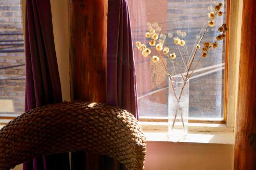 a vase with flowers in it sitting on a window sill at Jayden NAXI Healing Lodge臣安纳西疗愈小院 - Namaste in Lijiang