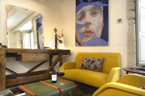 a living room with a yellow couch and a painting at Nicotera Apartment in Noto
