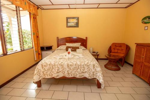 a bedroom with a bed and a chair at Hotel La Rosa de America in Alajuela City