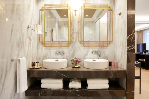 a bathroom with two sinks and a mirror and towels at The Excelsior - Small Luxury Hotels of the World in Thessaloniki