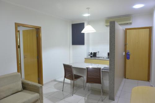 a kitchen with a table, chairs and a refrigerator at Oitis Hotel in Goiânia