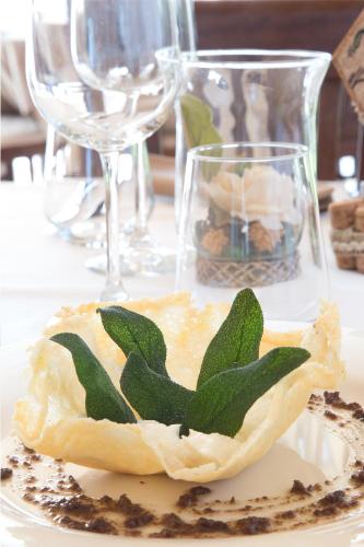 a piece of food with green leaves on a plate at Draconerium Hotel in Dronero