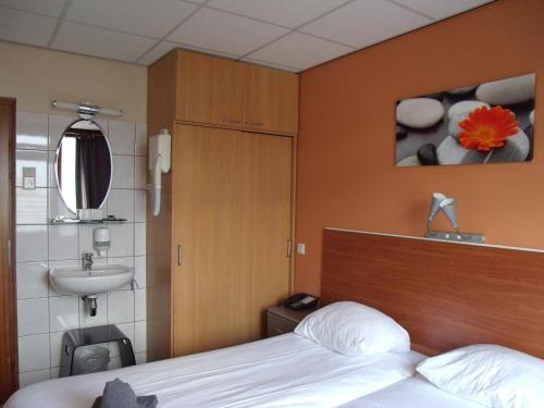 - une chambre avec un lit, un lavabo et une double vasque dans l'établissement Zorn Hotel Duinlust, à Noordwijk aan Zee