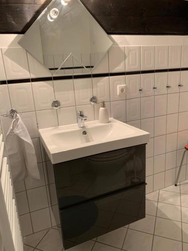 a white bathroom with a sink and a mirror at Ferienwohnung Mountainlook in Hohegeiß