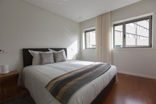 a bedroom with a large bed and two windows at Braga Luxury Residence 3854 in Braga