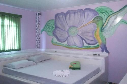 1 dormitorio con una pintura floral en la pared en OYO TBS Hotel, en Manacapuru