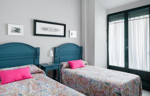 セビリアにあるCasa San Martín Sevillaのベッドルーム(ピンクの枕付きのベッド2台付)