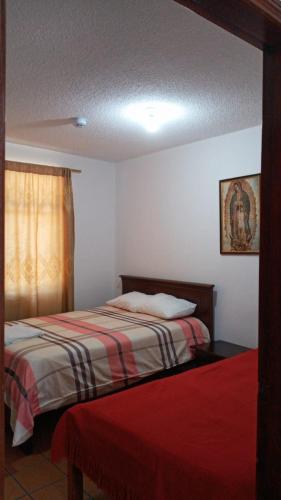 a hotel room with two beds and a window at Casa del Peregrino Santo Thomas in Baños