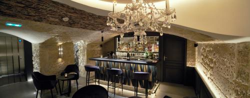 a bar in a room with a chandelier at Hôtel Roi de Sicile - Rivoli in Paris