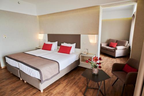 a hotel room with a large bed and a couch at Ramada Plaza by Wyndham Thraki in Alexandroupoli