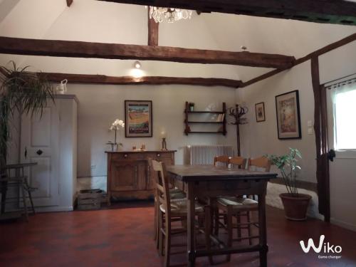 a dining room with a wooden table and chairs at La Chaumière aux Faisans in Ablon