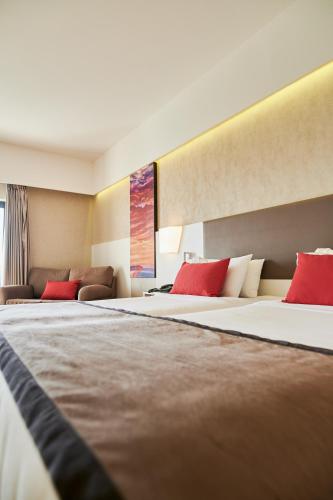 two beds in a hotel room with red pillows at Ramada Plaza by Wyndham Thraki in Alexandroupoli
