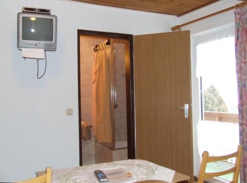 Pokój z telewizorem na ścianie ze stołem w obiekcie Pension Sonnenhof w mieście Bischofsmais