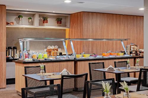 a restaurant with tables and chairs and a counter at Slaviero Curitiba Aeroporto in São José dos Pinhais