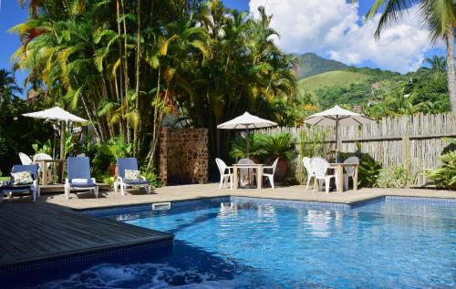 einen Pool mit Stühlen, Tischen und Sonnenschirmen in der Unterkunft Ilha Deck Hotel in Ilhabela