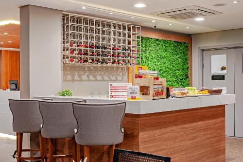 a kitchen with a bar with chairs at a counter at Slaviero Curitiba Aeroporto in São José dos Pinhais