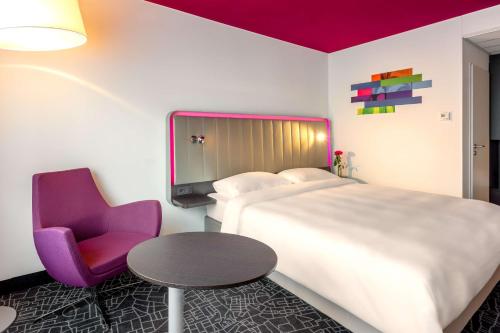a hotel room with a large bed and a purple chair at Park Inn by Radisson Nürnberg in Nuremberg