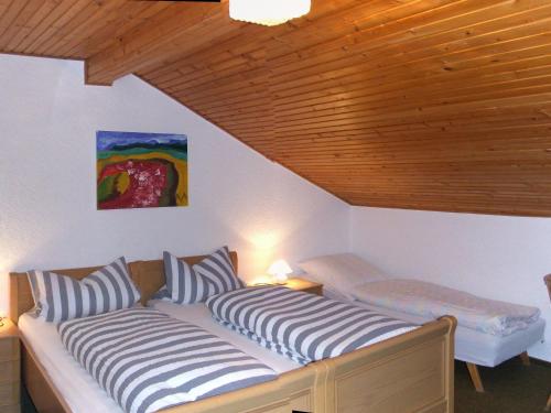 two beds in a room with a wooden ceiling at Pension Sonnenhof in Bischofsmais