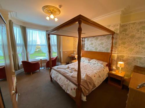 1 dormitorio con cama con dosel y escritorio en Clarence House, en Skegness