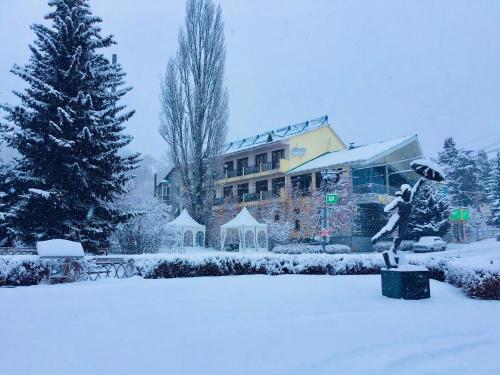 un patio cubierto de nieve con un edificio y un árbol de Navidad en Hotel - Saya, en Tsaghkadzor