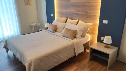 una camera da letto con un grande letto bianco con testiera in legno di Casa Dalè ad Altamura