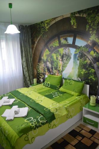 a bedroom with a green bed with a painting on the wall at Green rooms Hunedoara in Hunedoara