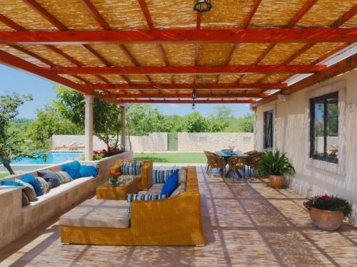 Villa Antonija في سيليبي: فناء مع أريكة وكراسي تحت بروغولا خشبية