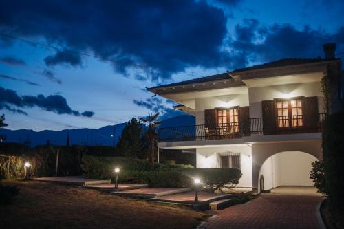 a white house with a balcony at night at Mythic House in Leptokaria