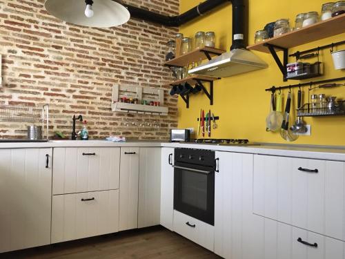 una cocina con armarios blancos y una pared de ladrillo en La Cobacha, en Cazalla de la Sierra
