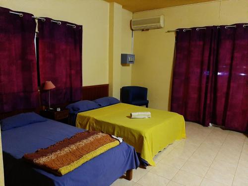 a room with two beds and a table and curtains at Latanier Beach Hotel in Grand-Baie