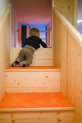 a young boy climbing stairs in a wooden play house at Hotel Garni Ransburgerhof in Flachau