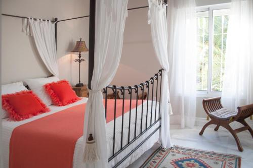 エル・プエルト・デ・サンタマリアにあるVilla de Lujo con Jardines y Piscinaのベッドルーム1室(赤い枕と椅子付きのベッド1台付)