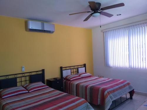 a bedroom with two beds and a ceiling fan at Depto Las Puertas la Ria #5 in Campeche