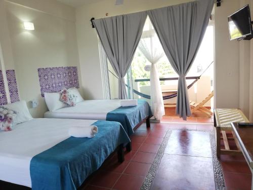 a hotel room with two beds and a balcony at Casa Puerto Bonito & Private Coworking in Puerto Escondido