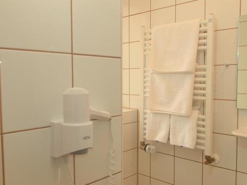 ein Bad mit weißen Handtüchern an der Wand in der Unterkunft Pension Friedrich Voss in Langeoog
