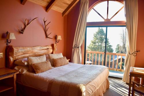 a bedroom with a bed and a large window at Hotel & Apart Hotel Monte Verde in Pucón