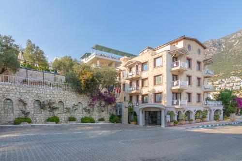 um edifício numa rua ao lado de uma parede de pedra em Oasis Hotel em Kalkan