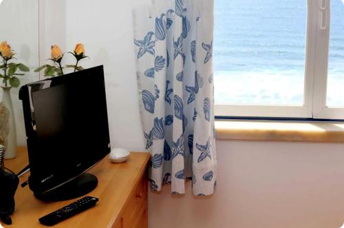 un monitor de ordenador sentado en un escritorio junto a una ventana en Beach House Above the Ocean AA3, en Ericeira