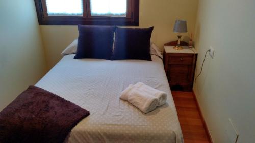 a small bedroom with a bed with blue pillows at O Candil De Santa Ana in Pontevedra