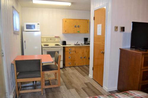 a small kitchen with a table and a refrigerator at The Villager Motel in Burstall