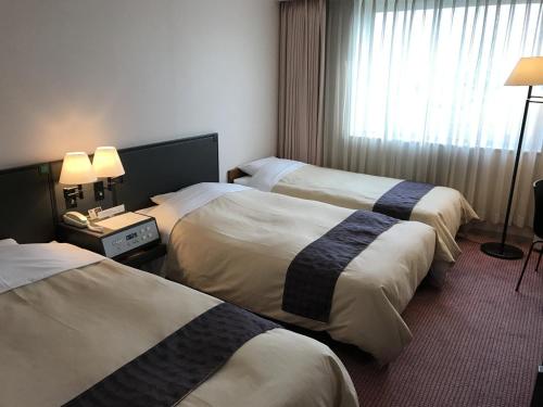 a hotel room with three beds and a window at Ogaki Forum Hotel / Vacation STAY 72183 in Ogaki