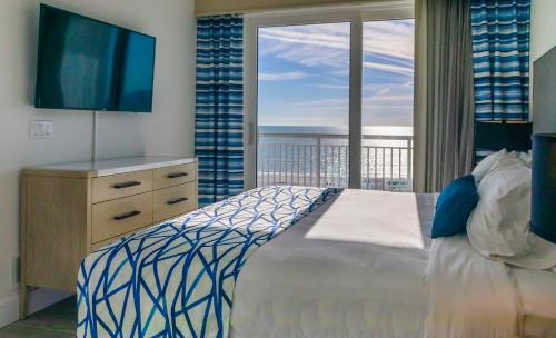 a bedroom with a bed and a television and a balcony at Provident Oceana Beachfront Suites in St Pete Beach