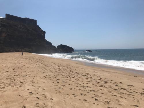 a person walking on a sandy beach near the ocean at L'Escale au Portugal Villa-B&B-Spa in Ataíja de Baixo