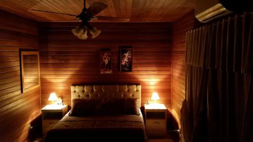 a bedroom with wooden walls and a bed with two lamps at LINDA CASA DE CAMPO in Viamão