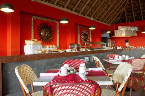 a restaurant with red walls and tables and chairs at Decameron Isla Coral Guayabitos, Ramada All-Inclusive Resort in Rincon de Guayabitos