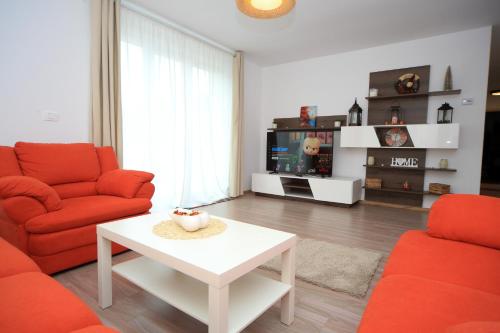 a living room with two red chairs and a coffee table at Carpen View Residence in Săcele