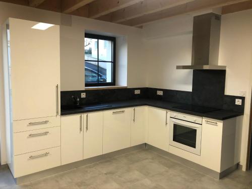 a kitchen with white cabinets and a black counter top at Logis de la Tonnellerie in Chambretaud
